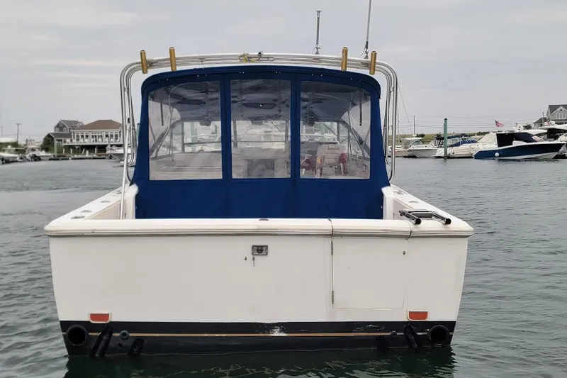Slide: The Image of 1996 Phoenix 34 Tournament boat docked in a marina, rear view with blue canopy. - 24