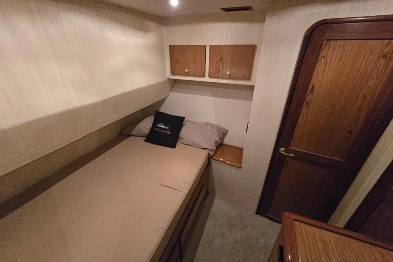 Slide: The Image of 1986 Ocean Yachts 55 Super Sport cabin with bed, wooden cabinets, and door. - 29