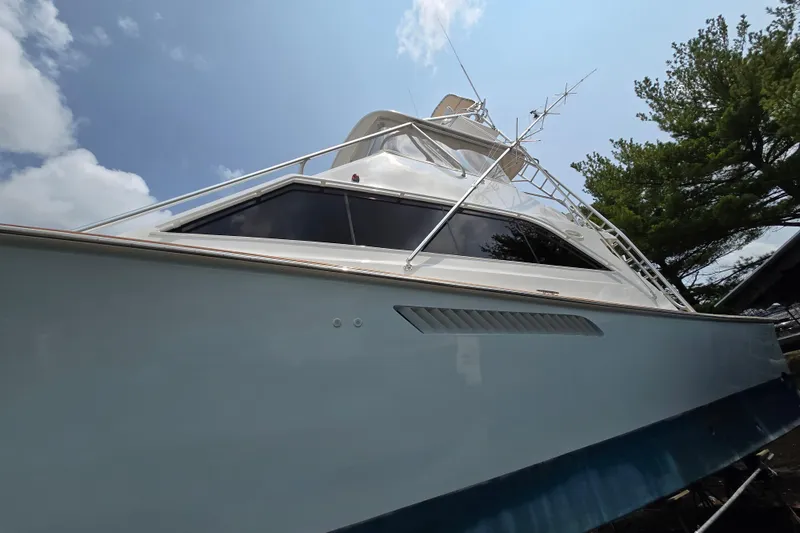 Slide: The Image of 1986 Ocean Yachts 55 Super Sport boat with sleek design, viewed from below against blue sky. - 6