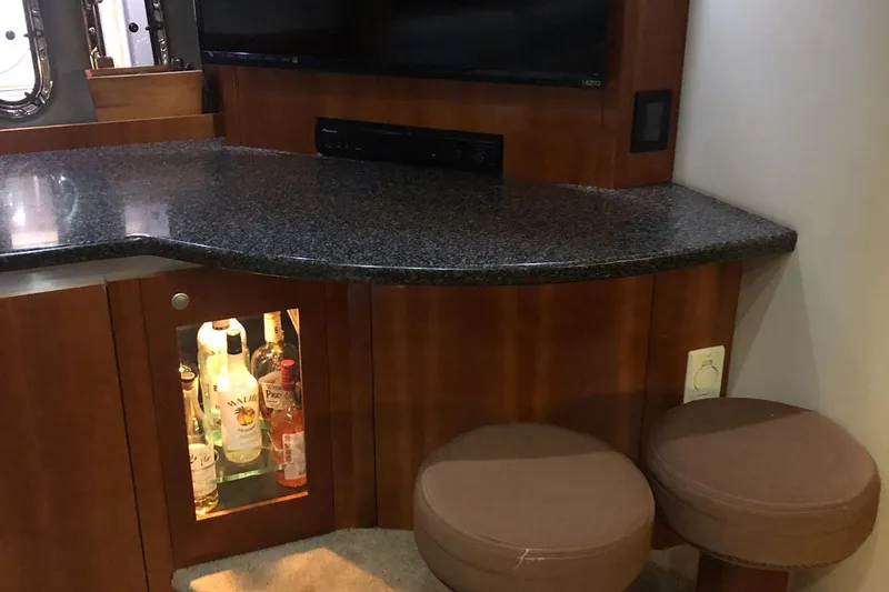Slide: The Image of 2006 Cruisers Yachts 420 Express interior bar area with stools and liquor cabinet. - 19