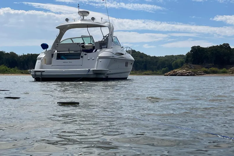 Slide: The Image of 2006 Cruisers Yachts 420 Express anchored on a serene lake with scenic background. - 2