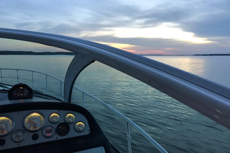 Slide: The Image of 2006 Cruisers Yachts 420 Express dashboard view at sunset over calm waters. - 33