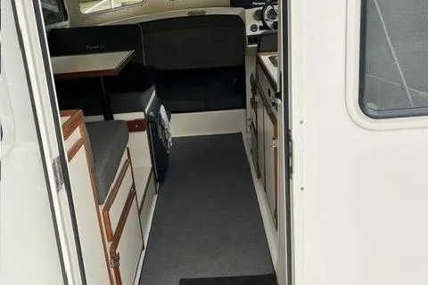 Slide: The Image of 2007 C-Dory Tomcat 255 Pilothouse interior with seating, cabinetry, and helm. - 13