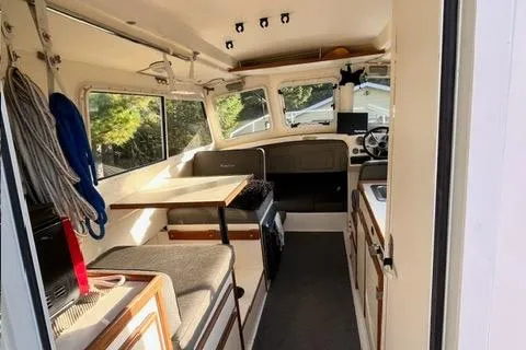 Slide: The Image of 2007 C-Dory Tomcat 255 Pilothouse interior with seating, table, and helm. - 4