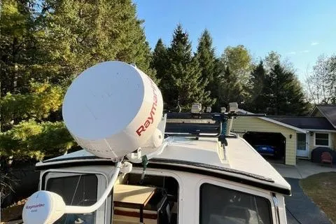 Slide: The Image of 2007 C-Dory Tomcat 255 Pilothouse with Raymarine radar, parked near trees and a garage. - 5