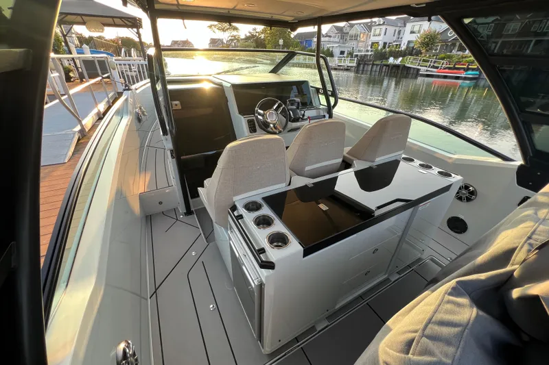 Slide: The Image of 2023 Saxdor 320 GTO boat interior with modern helm and seating, docked by waterfront homes. - 12