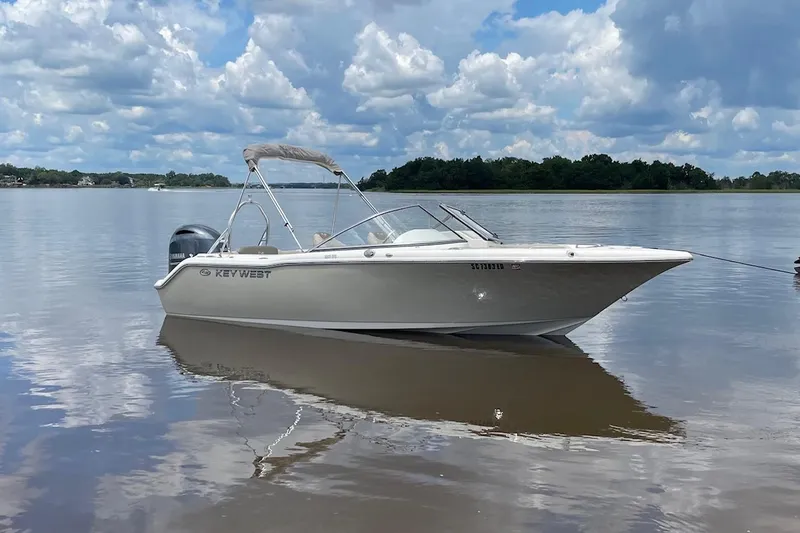 Slide: The Image of 2023 Key West 203 DFS boat on calm lake under cloudy sky. - 0