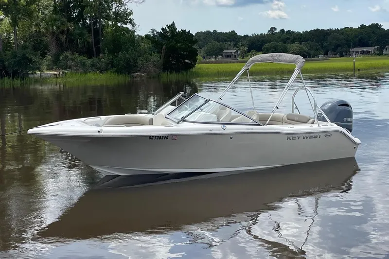 Slide: The Image of 2023 Key West 203 DFS boat on calm water with lush greenery in the background. - 1