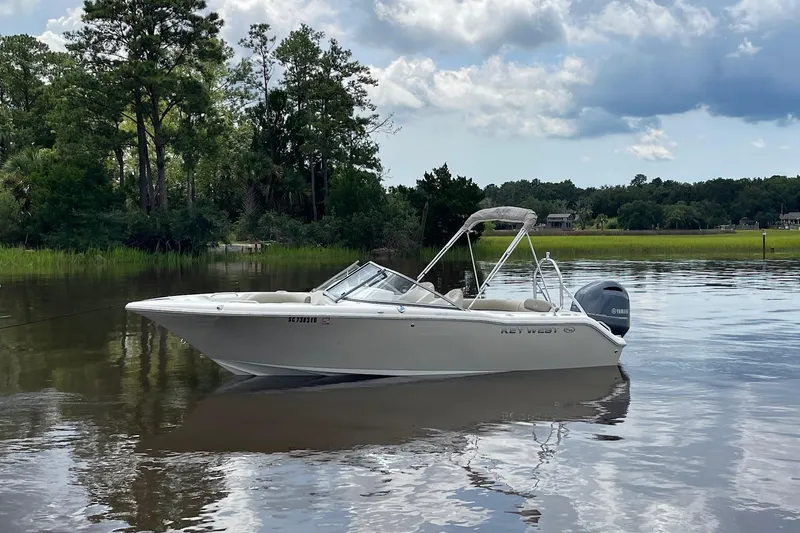 Slide: The Image of 2023 Key West 203 DFS boat on calm water, surrounded by lush greenery. - 3