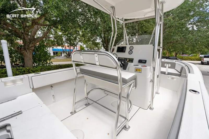 Slide: The Image of 2020 Release 210 RX boat interior with console and seating, surrounded by trees. - 14