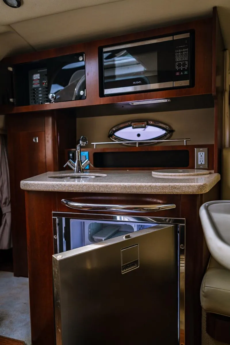 Slide: The Image of 2018 Chaparral 270 Signature yacht interior kitchen with microwave and stainless steel fridge. - 8