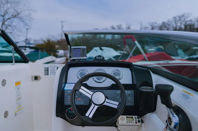 Slide: The Image of 2013 Sea Ray 240 Sundancer boat dashboard with steering wheel and controls. - 5