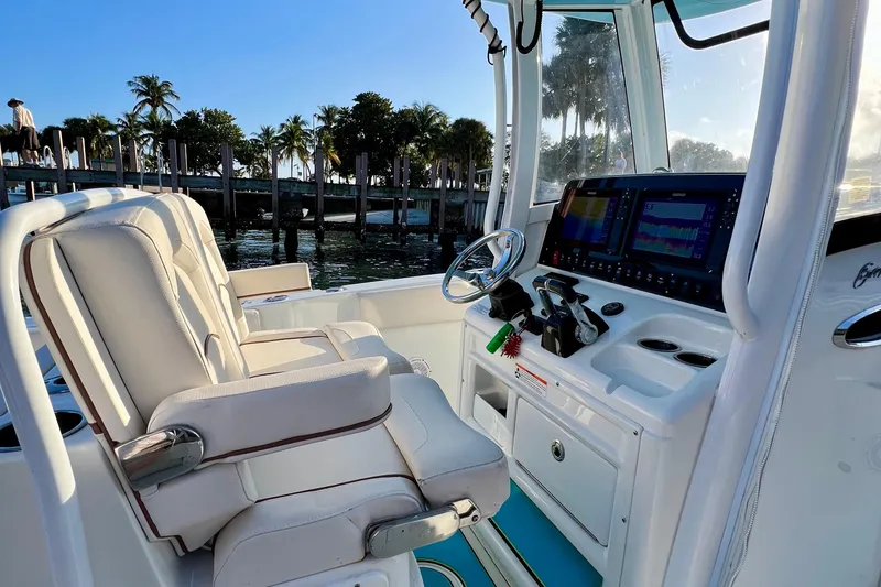 Slide: The Image of 2019 Sea Hunt 27 Gamefish CC boat interior with helm and seating, dockside view. - 5