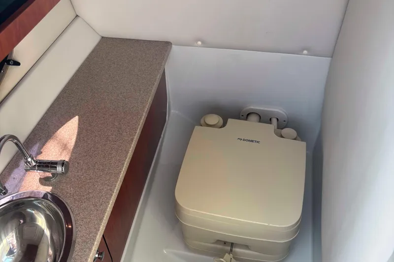 Slide: The Image of 2014 Crownline 285 SS boat interior with sink and Dometic portable toilet. - 13
