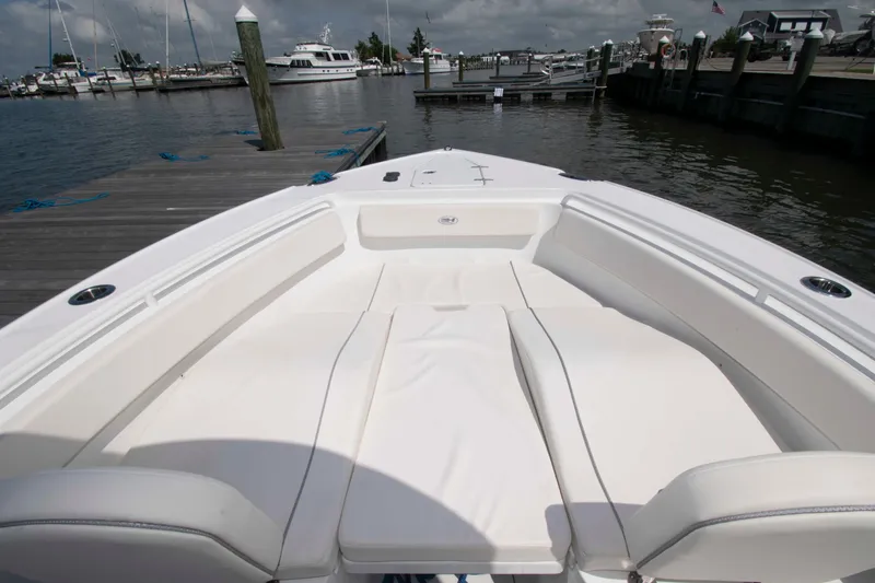 Slide: The Image of 2023 Sea Hunt Ultra 265 SE boat interior with white seating at a marina. - 13