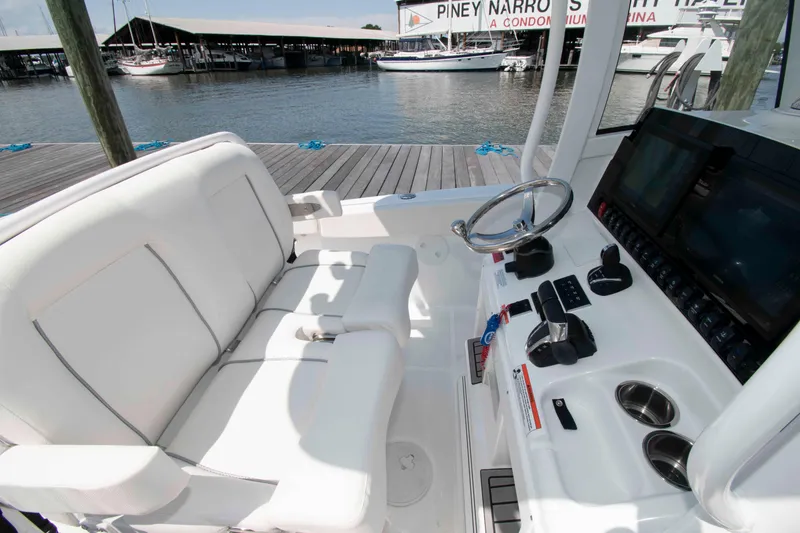 Slide: The Image of 2023 Sea Hunt Ultra 265 SE boat interior with helm and seating at marina. - 6