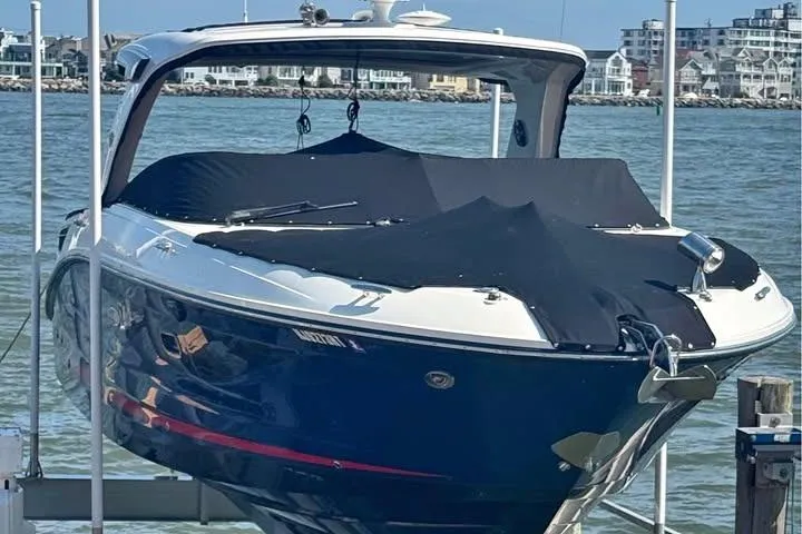 Slide: The Image of 2019 Sea Ray SLX 350 boat docked, covered, with waterfront buildings in the background. - 1
