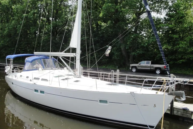 The Image of 2006 Beneteau Oceanis Clipper 423 sailboat docked near lush greenery. - 0