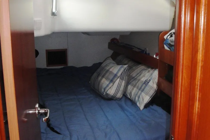 Slide: The Image of Cozy cabin interior of 2006 Beneteau Oceanis Clipper 423 with plaid pillows and blue bedding. - 30