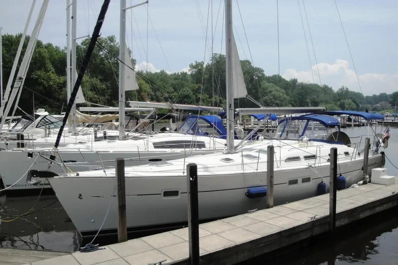 Slide: The Image of 2006 Beneteau Oceanis Clipper 423 sailboat docked at a marina with blue canopies. - 33