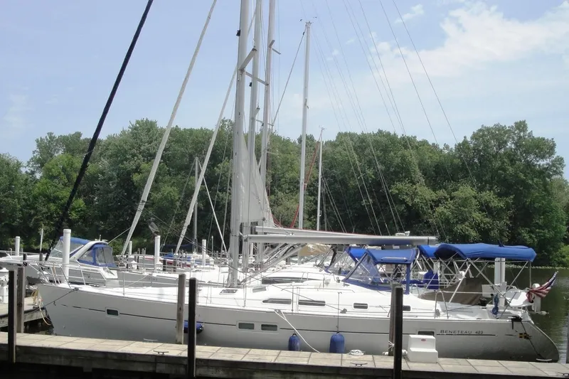 Slide: The Image of 2006 Beneteau Oceanis Clipper 423 sailboat docked at a marina with lush trees. - 34