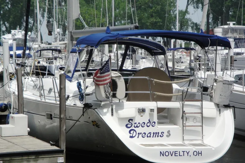 Slide: The Image of 2006 Beneteau Oceanis Clipper 423 sailboat docked, featuring blue canopy and American flag. - 35