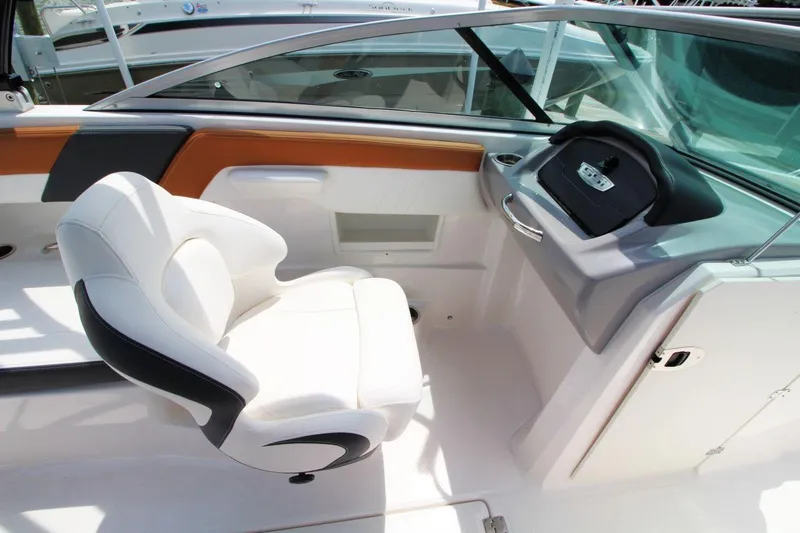 Slide: The Image of 2024 Chaparral 235 SSi OB boat interior with white captain's chair and sleek dashboard. - 11