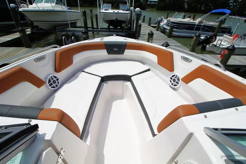 Slide: The Image of 2024 Chaparral 235 SSi OB boat interior with stylish seating and speakers at a dock. - 14