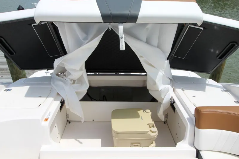 Slide: The Image of 2024 Chaparral 235 SSi OB boat interior with storage compartment and portable toilet. - 16