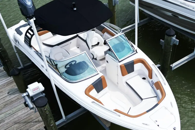 Slide: The Image of 2024 Chaparral 235 SSi OB boat with sleek design, docked on water. - 6