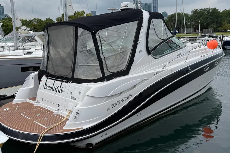 Slide: The Image of 2008 Four Winns V358 boat docked, featuring sleek design and covered cockpit. - 10