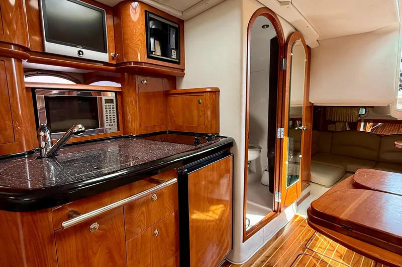 Slide: The Image of Luxurious 2008 Four Winns V358 yacht interior with kitchenette, wood cabinetry, and seating area. - 3