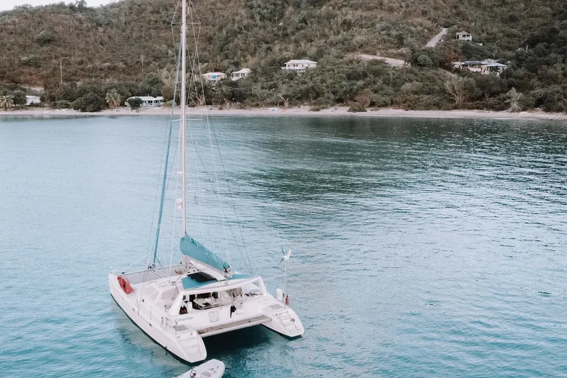 Slide: The Image of Catamaran Voyage 440 (2001) anchored in tranquil bay with lush hillside backdrop. - 1