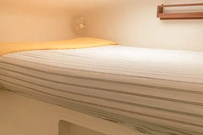 Slide: The Image of Cozy cabin bed in 2001 Voyage 440 yacht with striped bedding and wooden shelf. - 16