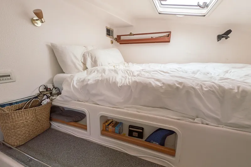 Slide: The Image of Cozy cabin bedroom in 2001 Voyage 440 yacht with white bedding and storage shelves. - 28