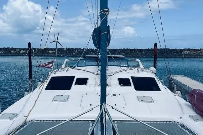 Slide: The Image of 2001 Voyage 440 catamaran docked in a serene marina with clear skies. - 3