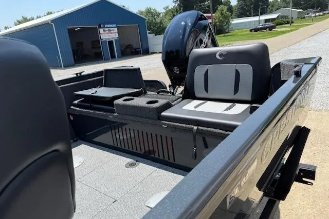 Slide: The Image of 2026 Crestliner 1650 Kodiak boat interior with seating and motor, parked near a blue building. - 7