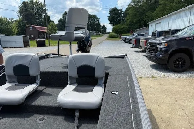 Slide: The Image of 2026 Crestliner 1600 Storm boat with gray seating, parked outdoors near vehicles. - 8