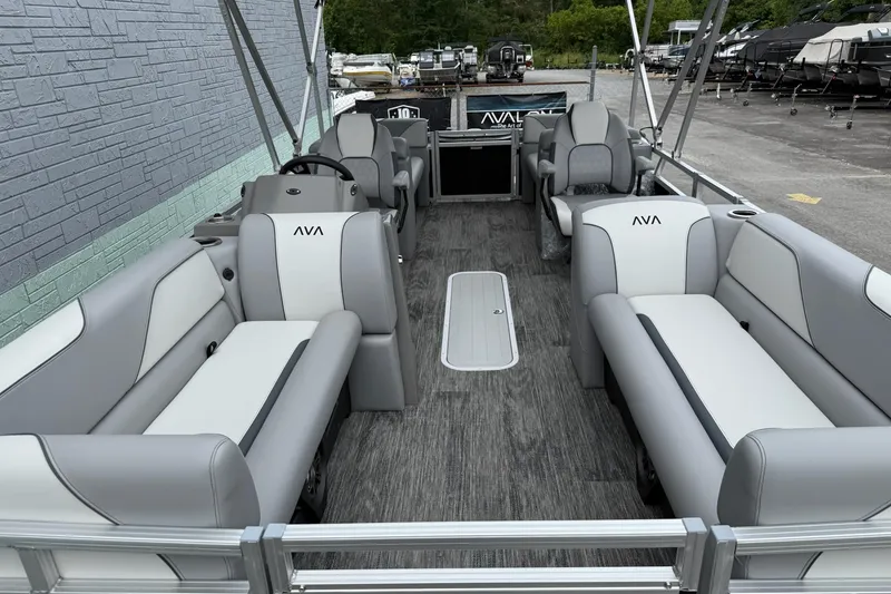 Slide: The Image of 2025 Avalon Venture Quad Lounger 2180 interior with gray and white seating, docked outdoors. - 9