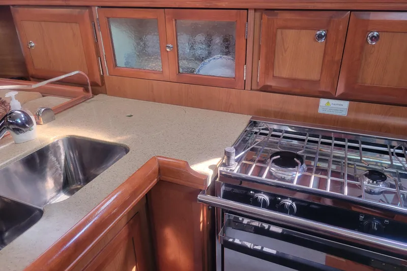 Slide: The Image of 2009 Hunter 38 yacht kitchen with stainless steel sink, stove, and wooden cabinetry. - 24