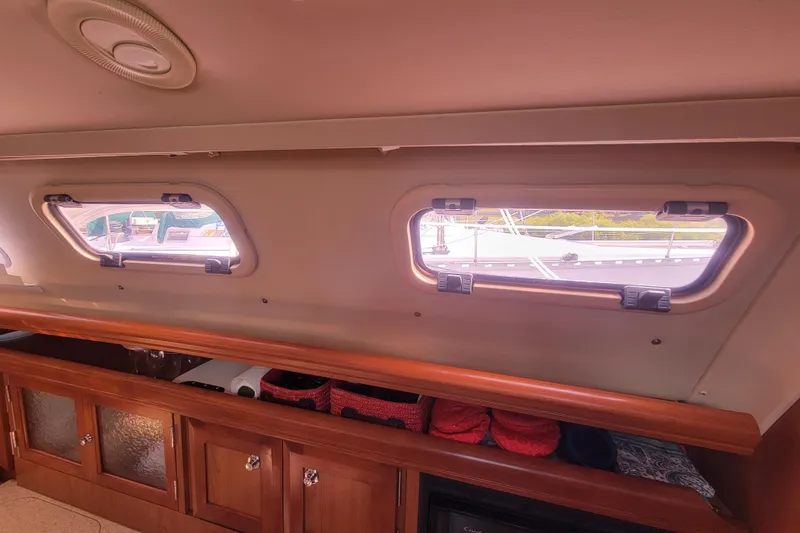 Slide: The Image of Interior view of a 2009 Hunter 38 sailboat, featuring cabin windows and wooden cabinetry. - 39