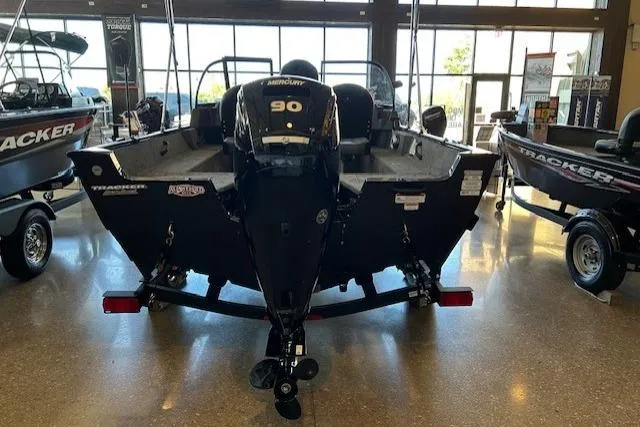 Slide: The Image of 2026 Tracker Pro Guide V-16 WT boat with Mercury 90 engine in showroom. - 2