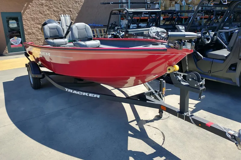 The Image of Red 2025 Tracker Super Guide V-16 T boat on trailer, parked outdoors. - 0