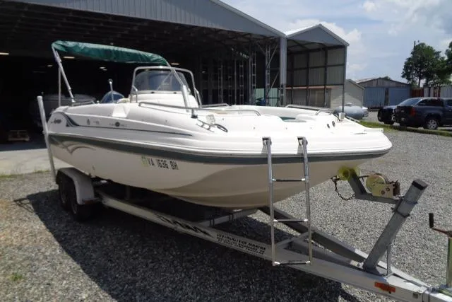 Slide: The Image of 2005 Hurricane GS211 boat on trailer, parked outside a large garage. - 4