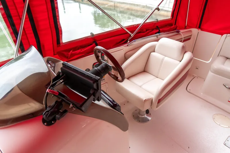 Slide: The Image of 1999 Chaparral 252 Sunesta boat interior with red canopy and beige captain's chair. - 18