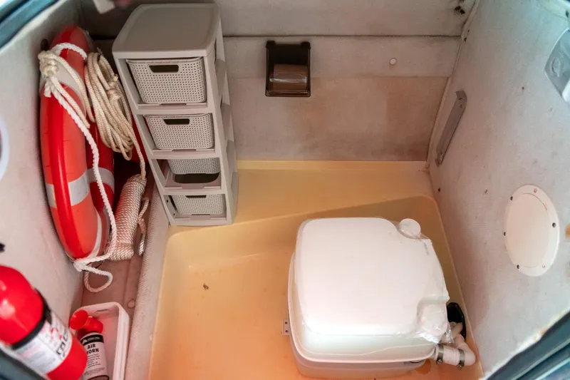 Slide: The Image of Interior of 1999 Chaparral 252 Sunesta boat with storage, life preserver, and portable toilet. - 23