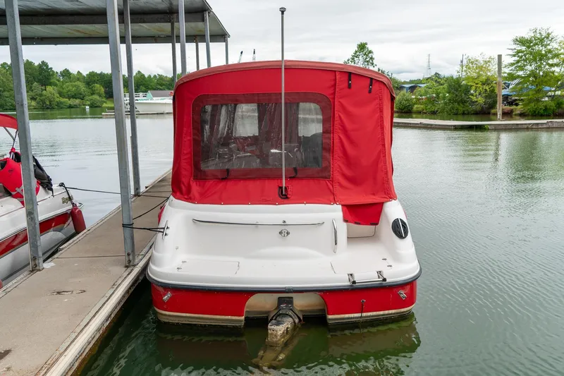 Slide: The Image of 1999 Chaparral 252 Sunesta boat with red canopy docked on a calm lake. - 4