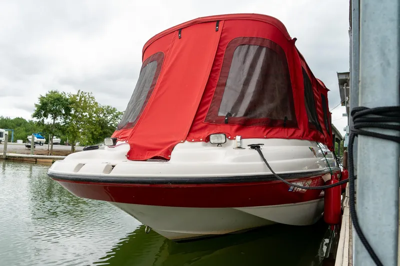 Slide: The Image of 1999 Chaparral 252 Sunesta boat with red canopy docked on a calm lake. - 5