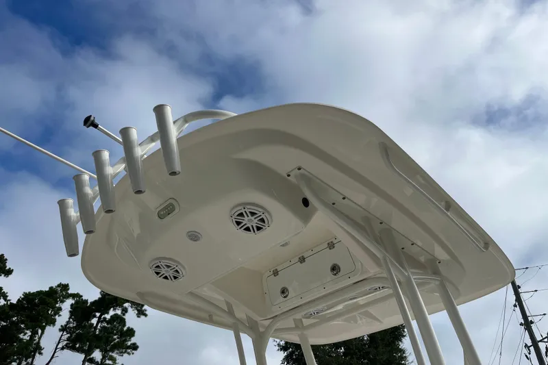 Slide: The Image of 2020 Cobia 201 Center Console boat top view with rod holders and speakers against cloudy sky. - 23