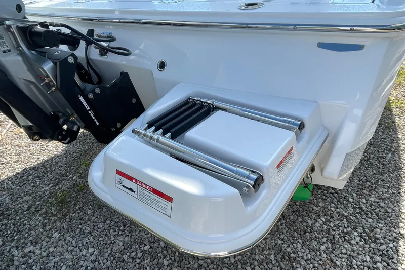 Slide: The Image of 2026 Blackfin 242HB boat with a swim platform and ladder on gravel surface. - 33